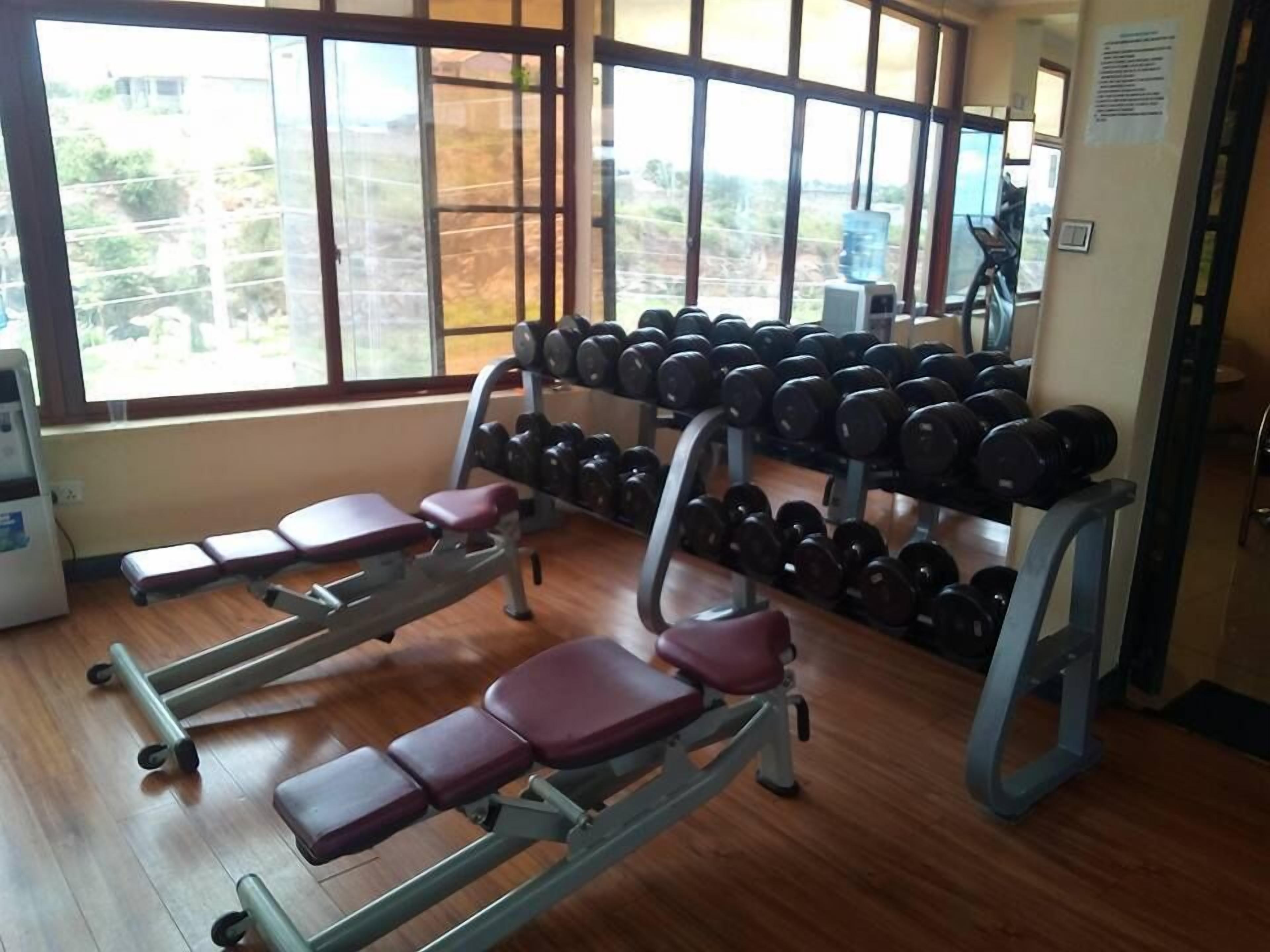 A gym with weightlifting equipment, benches, and dumbbells.