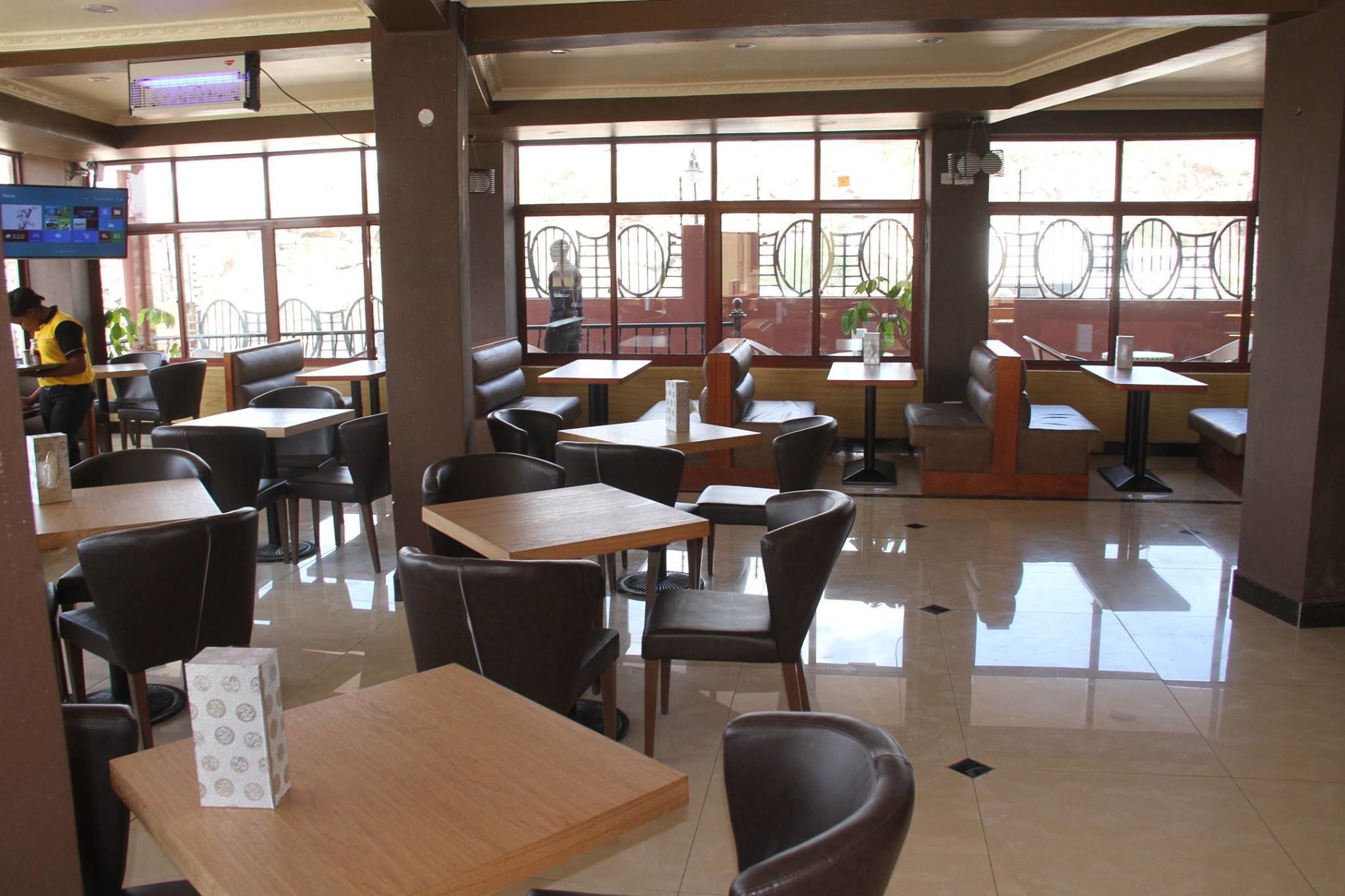 Un restaurante con cabinas y mesas, ventanas amplias y piso de baldosas.