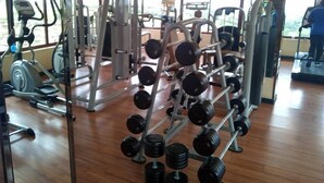 Un gimnasio con diversos equipos de ejercicio, incluyendo mancuernas y máquinas de pesas.