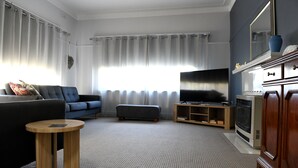 A living room with a sofa, a TV, a wooden side table, and a fireplace. - CURNOWS BENDIGO RENTAL (Golden Square)