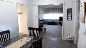 A dining area with a table and chairs, a living room with a sofa and a coffee table, and a hallway leading to another room. - CURNOWS BENDIGO RENTAL (Golden Square)