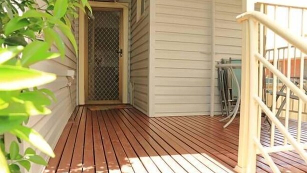 A wooden deck with a metal gate, a covered entryway, and a white exterior wall. - CURNOWS BENDIGO RENTAL (Golden Square)