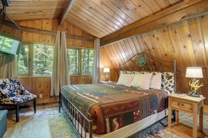 Une chambre dans une cabane en bois, avec un lit, une chaise, une table de chevet et une fenêtre.