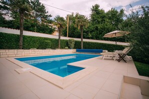 Una piscina al aire libre, camas de piscina gratis, sombrillas