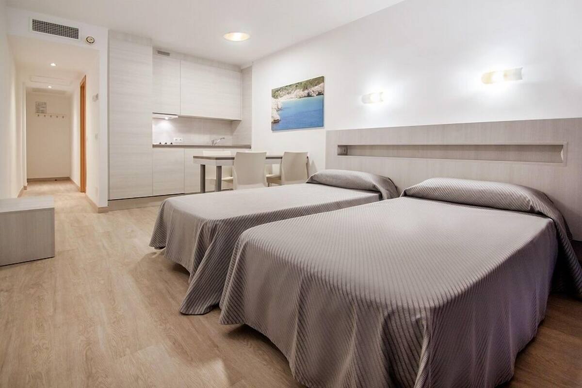 Habitación de hotel con dos camas, kitchenette y comedor.