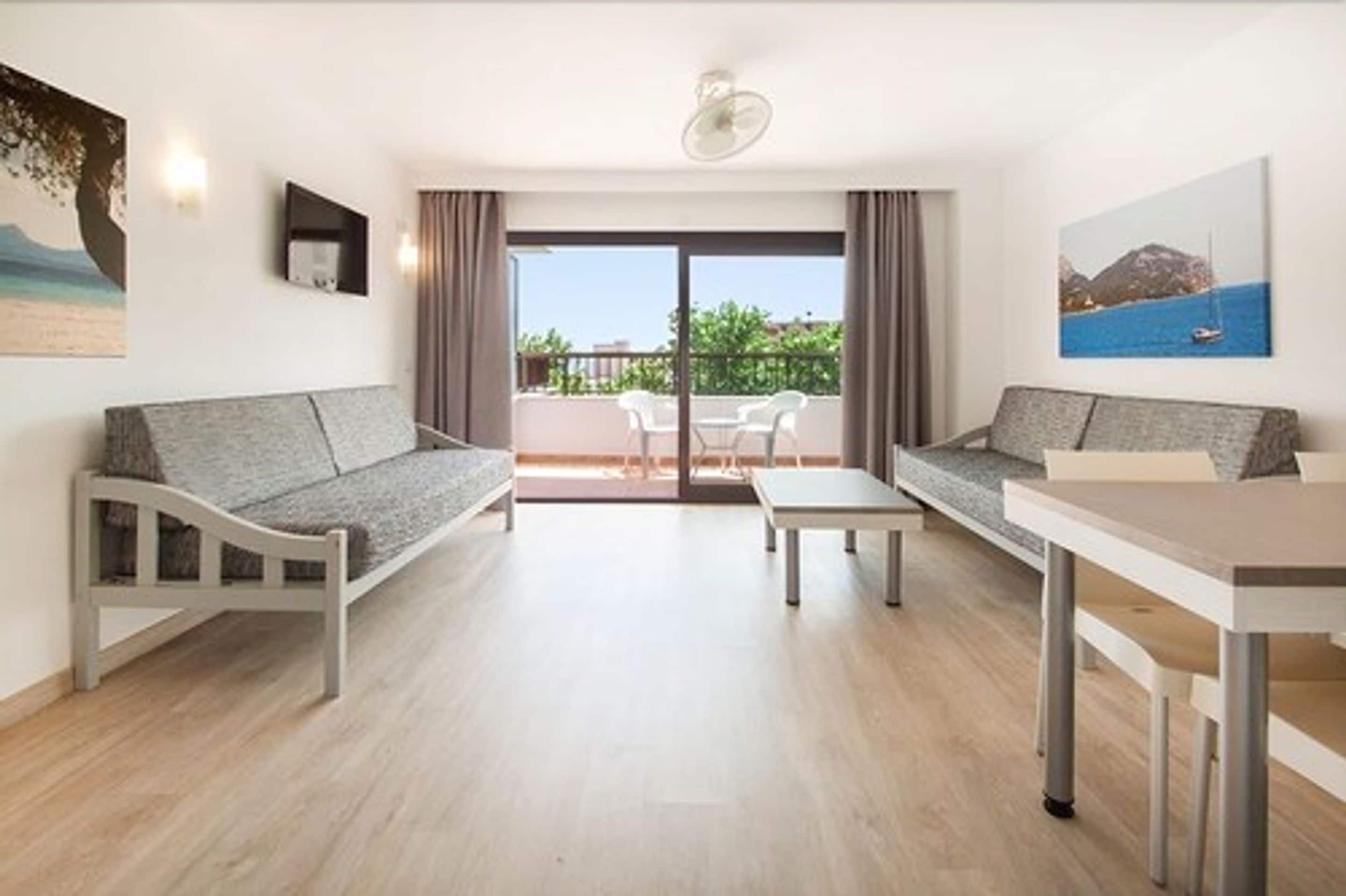 Una sala de estar moderna con un sofá, una mesa de comedor y un balcón con vista al mar.
