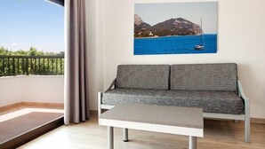 Un balcone con un divano e un tavolo, un quadro raffigurante una costa e vista sul mare e sulle montagne.