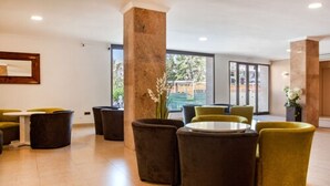 Una hall con tavoli e sedie rotonde, un'imponente colonna e vista sull'esterno.