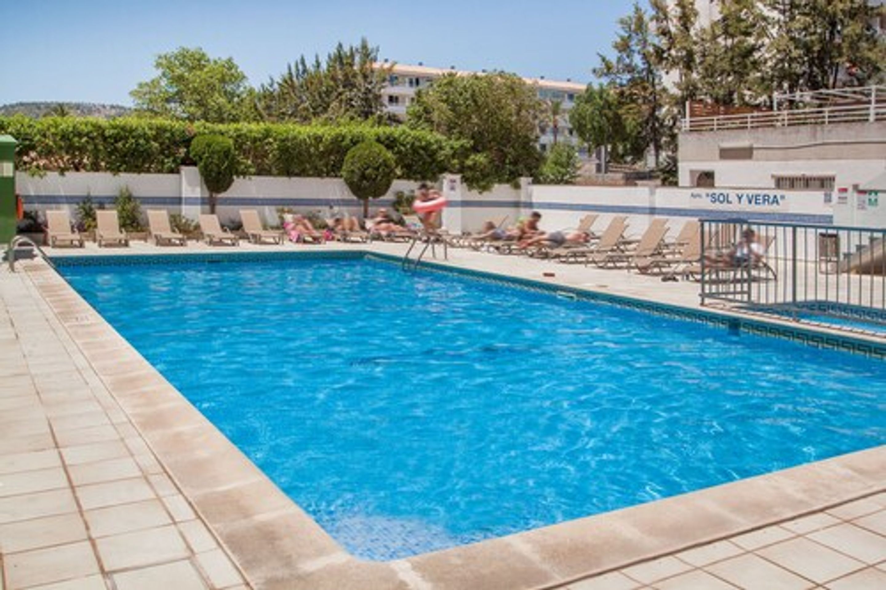 A swimming pool with lounge chairs and a sign that reads "SOL Y VERA".