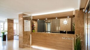 Una reception con finitura in legno, una sveglia e un cartello con su scritto 'SolyVerla'.
