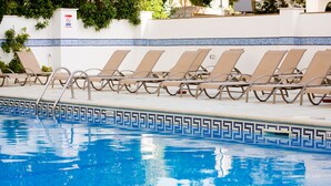 Una piscina con lettini e un bordo piastrellato.
