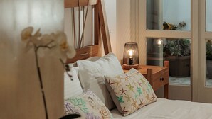 A bedroom with a bed, bedside tables, a nightstand, a lamp, and a view through a glass door.