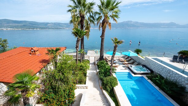 Ein Poolbereich mit Whirlpool, Palmen und Meerblick.