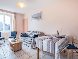 Een gezellige woonkamer met een bank, een eettafel en een raam met gordijnen.