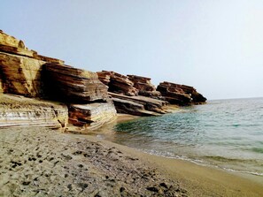 Una playa costera con formaciones rocosas escalonadas y una orilla arenosa.