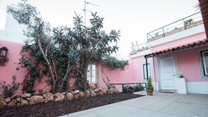 A pink building with a stone wall and a tree in the foreground.