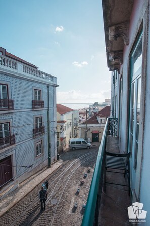 Une rue étroite bordée d’immeubles, avec une voie ferrée pour tramway et une voiture.
