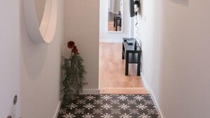 A hallway with a mirror, a potted plant, and a hanging sign.