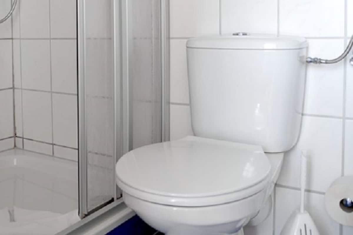 A bathroom with a toilet, a shower enclosure, and a toilet paper holder.