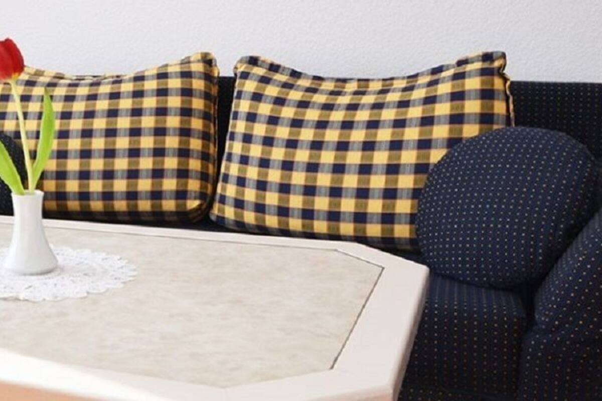 A living room with a white coffee table, a wicker chair, and a sofa with checkered cushions.