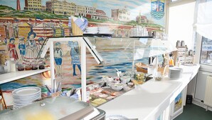 En buffet med forskellige retter, en glasudstillingsmontre og et muralmaleri med historiske personer.