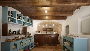 Eine rustikale Küche mit Holzbalken, Regalen mit Flaschen, einer Bar und einer Steinwand.
