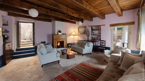 Ein gemütliches Wohnzimmer mit Kamin, bequemen Sitzmöglichkeiten und Blick ins Freie.