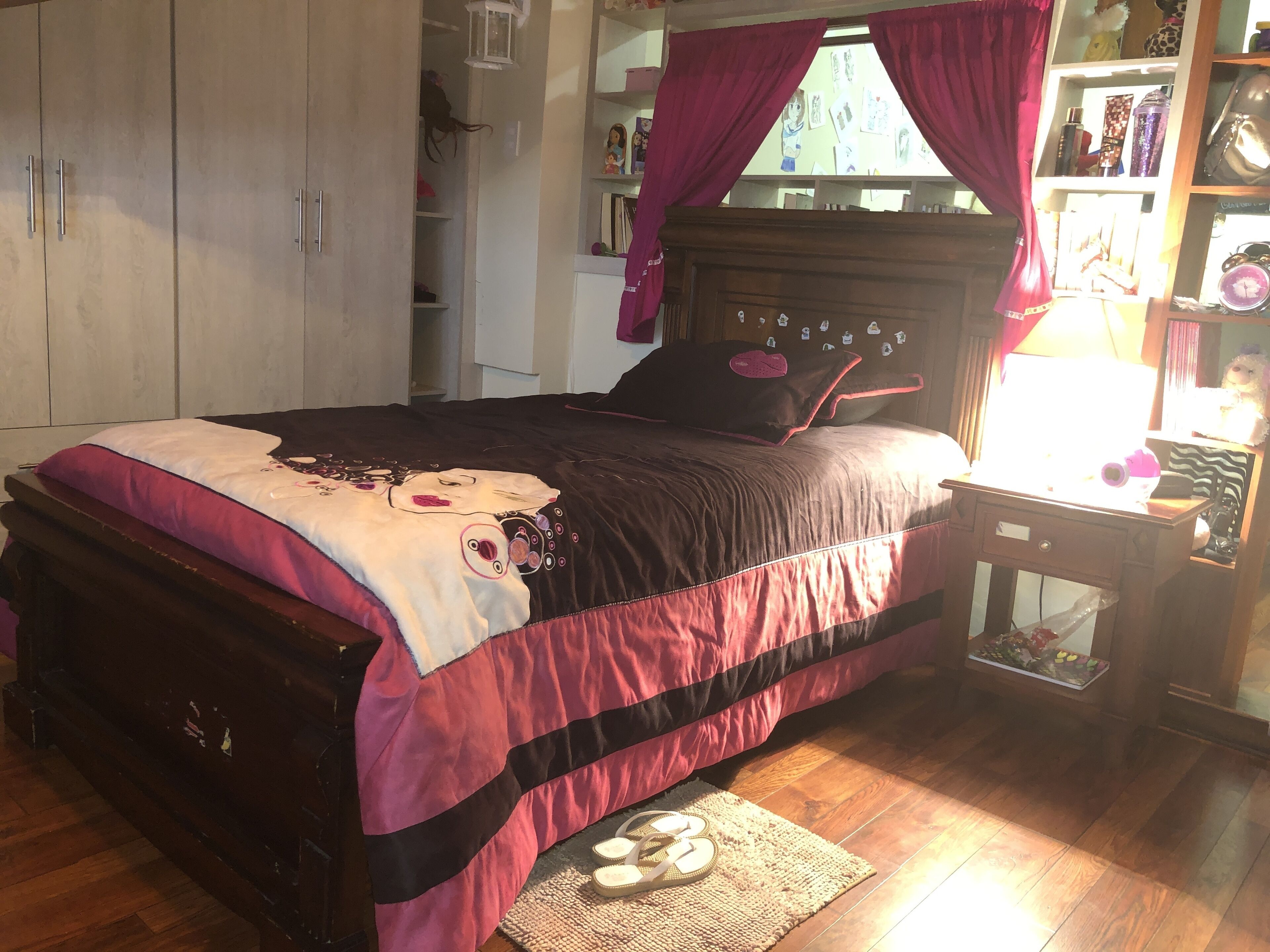 Une chambre à coucher comprenant un lit, une armoire, une table de chevet et une fenêtre avec des rideaux.