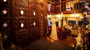 A wooden-paneled hallway with a staircase leading to an upper level. A decorative angel figure is illuminated in the center. - Hostal Dulce Hogar (Latacunga)