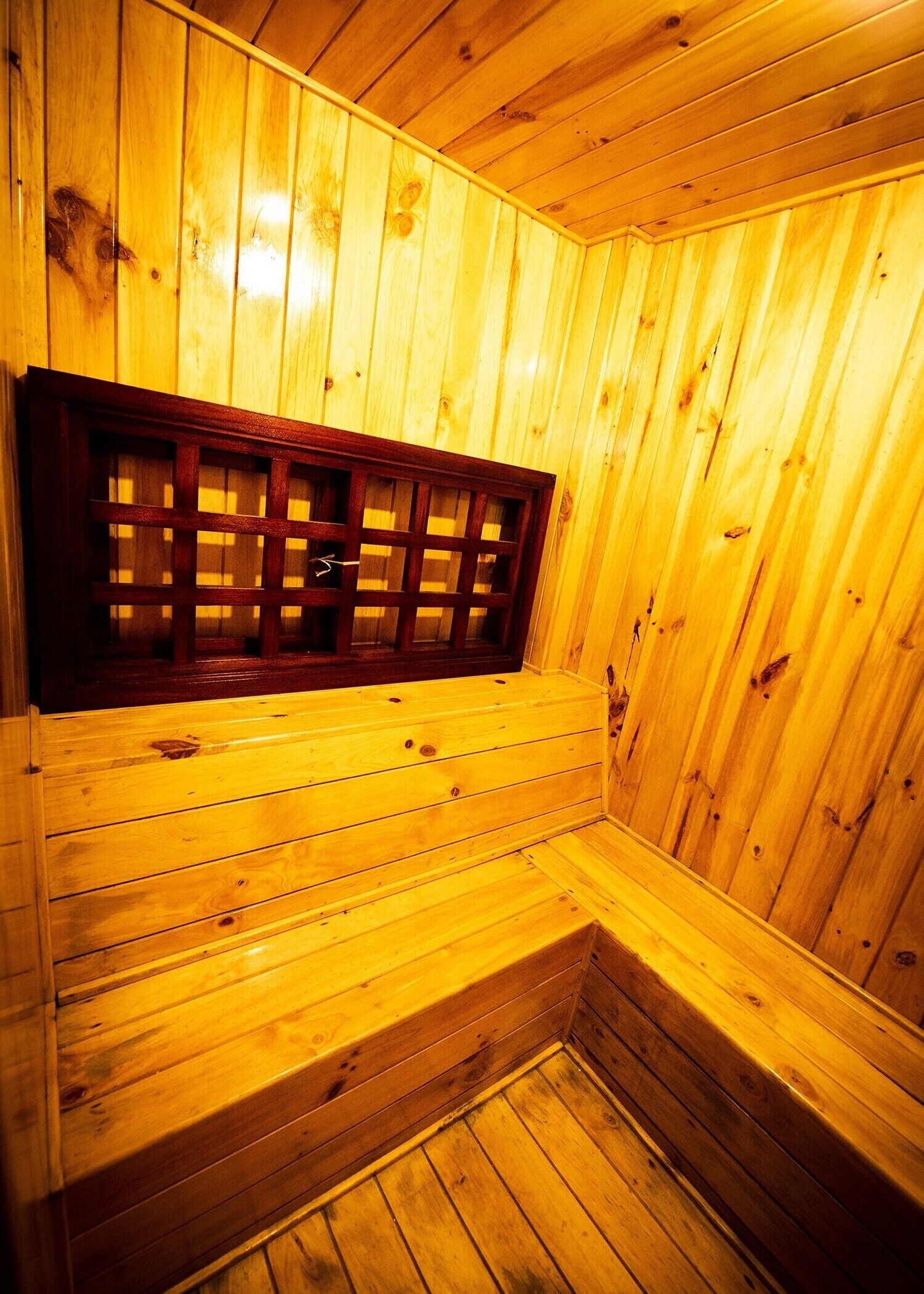 A wooden sauna with a bench and a window.