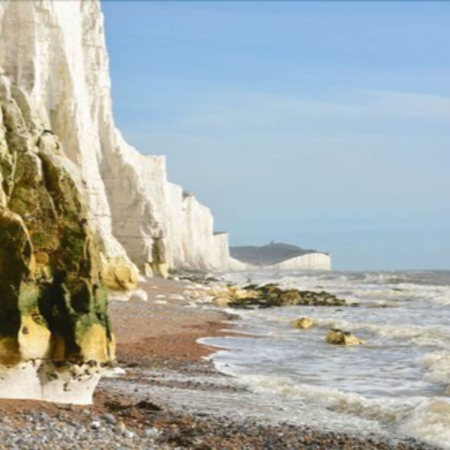 A coastal scene with white cliffs and a pebbly beach.