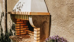 Forno de tijolos ao ar livre com um banco e um vaso de planta.