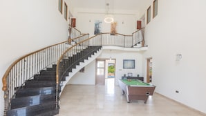 A spacious indoor area with a curved staircase, a pool table, and a door leading to another room. - Villa Jorja, Fabulous and luxurious 7BDR Villa, Close to Fig tree Bay Beach (Protaras)