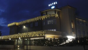Un hotel con un letrero que dice “HOTEL” y un balcón decorado con luces.