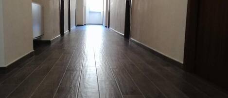 Un long couloir étroit, doté d’un plancher en bois foncé et de murs de couleur beige.