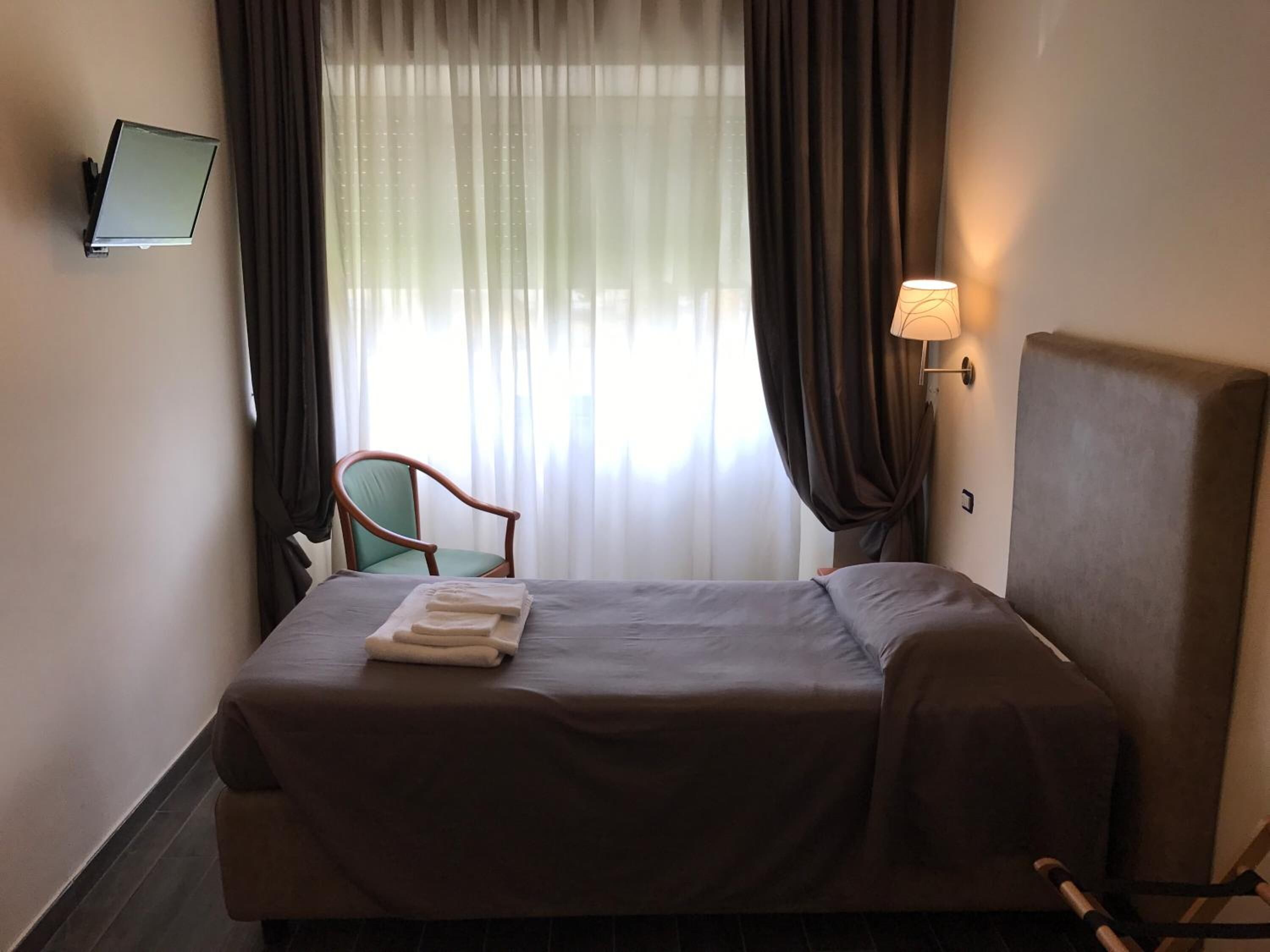 Une chambre d’hôtel avec un lit, une chaise, un bureau et une lampe.