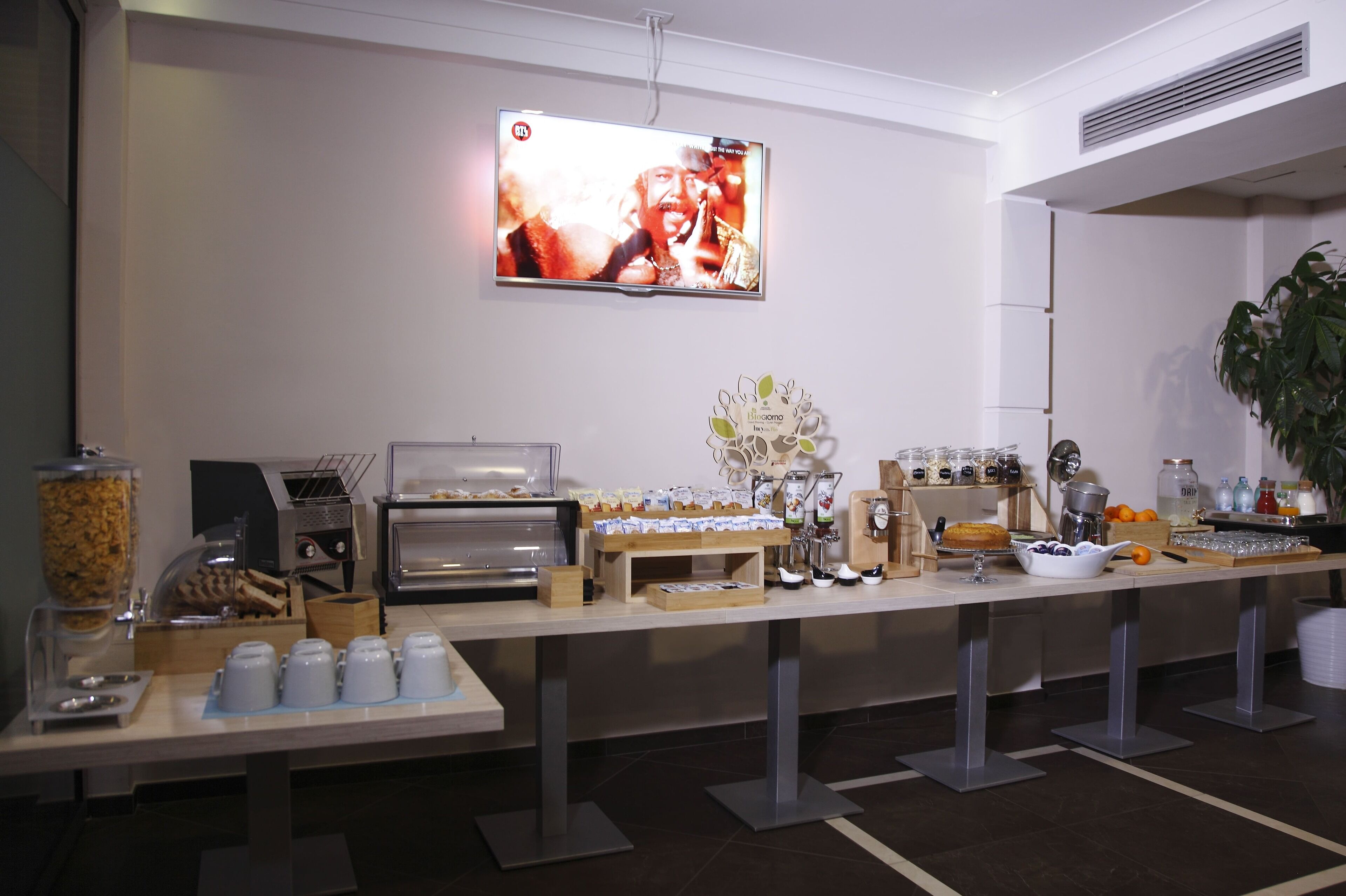 Ein Buffet mit einer Kaffeestation, Speisebehältern und einem an der Wand befestigten Fernseher.