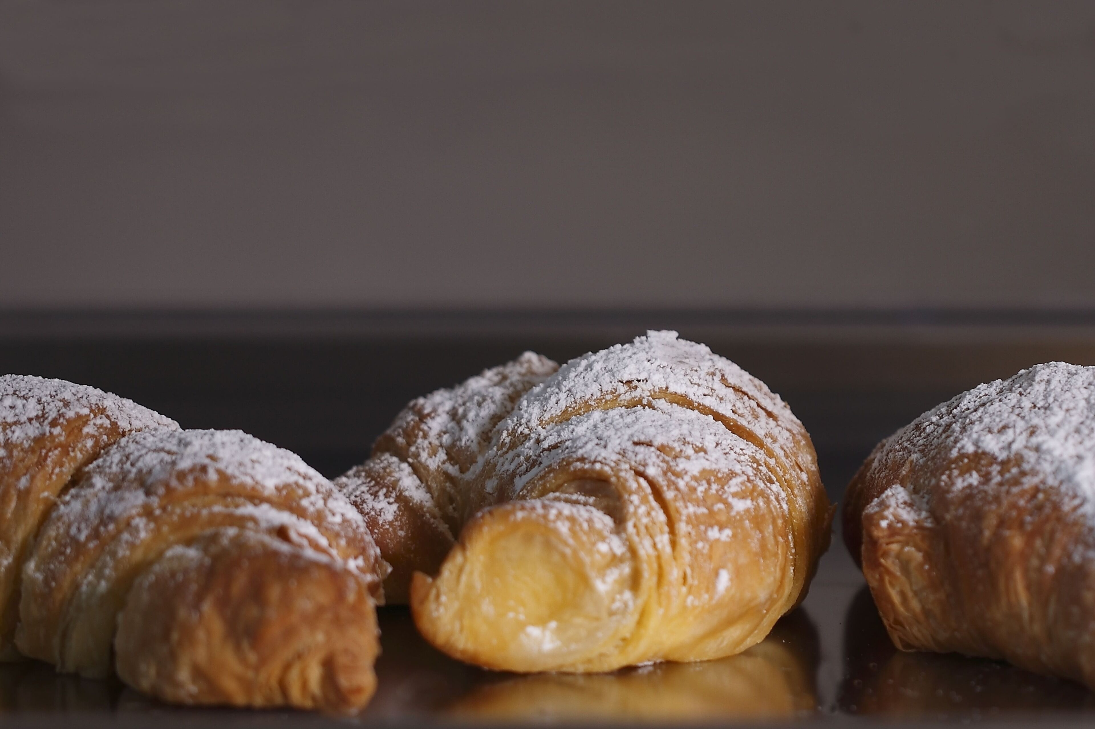 Three croissants dusted with powdered sugar.