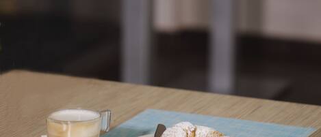 A table with a cup of coffee, a plate with a pastry, and a spoon.