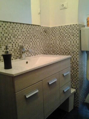A bathroom with a tiled backsplash, a sink, and a cabinet with drawers. - Emerald Fields (Florence)