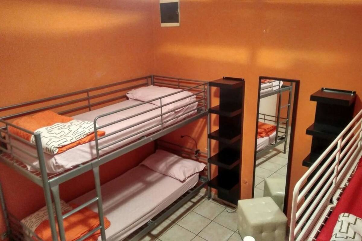 A bunk bed room with orange walls, a small window, and a white stool.