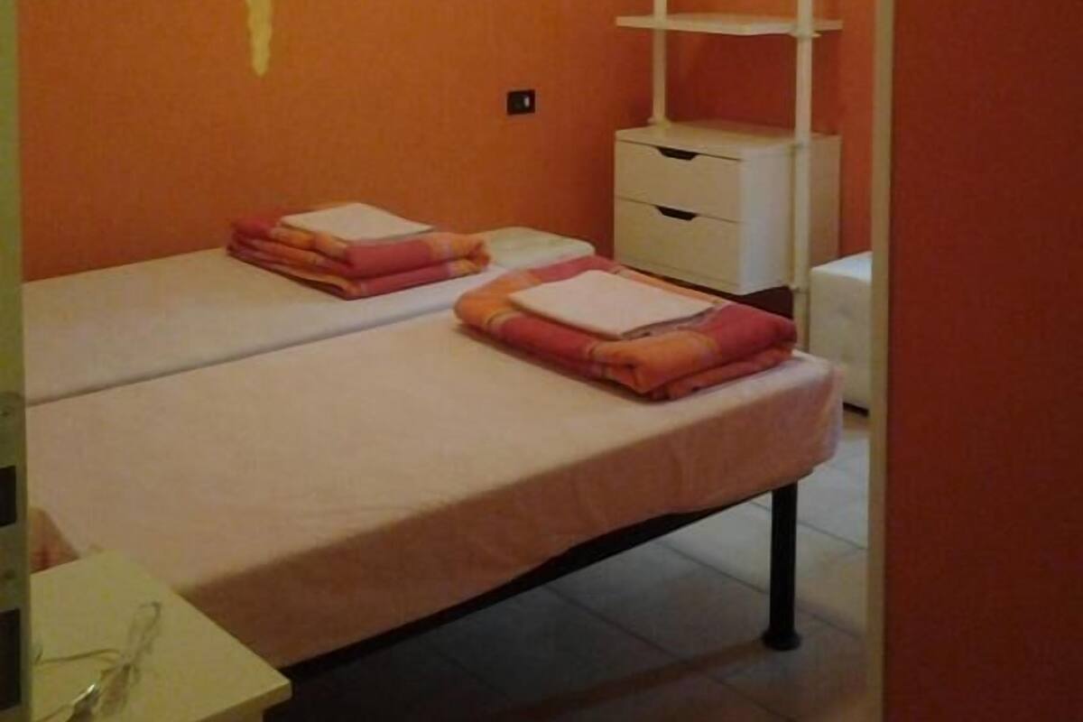 A bedroom with a bed, a nightstand, a dresser, and a wall with a sun mural.