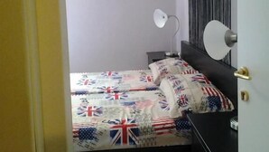 Ein Schlafzimmer mit einem Quilt-gebetteten Bett, einer Nachttischlampe und einem Wandbild.