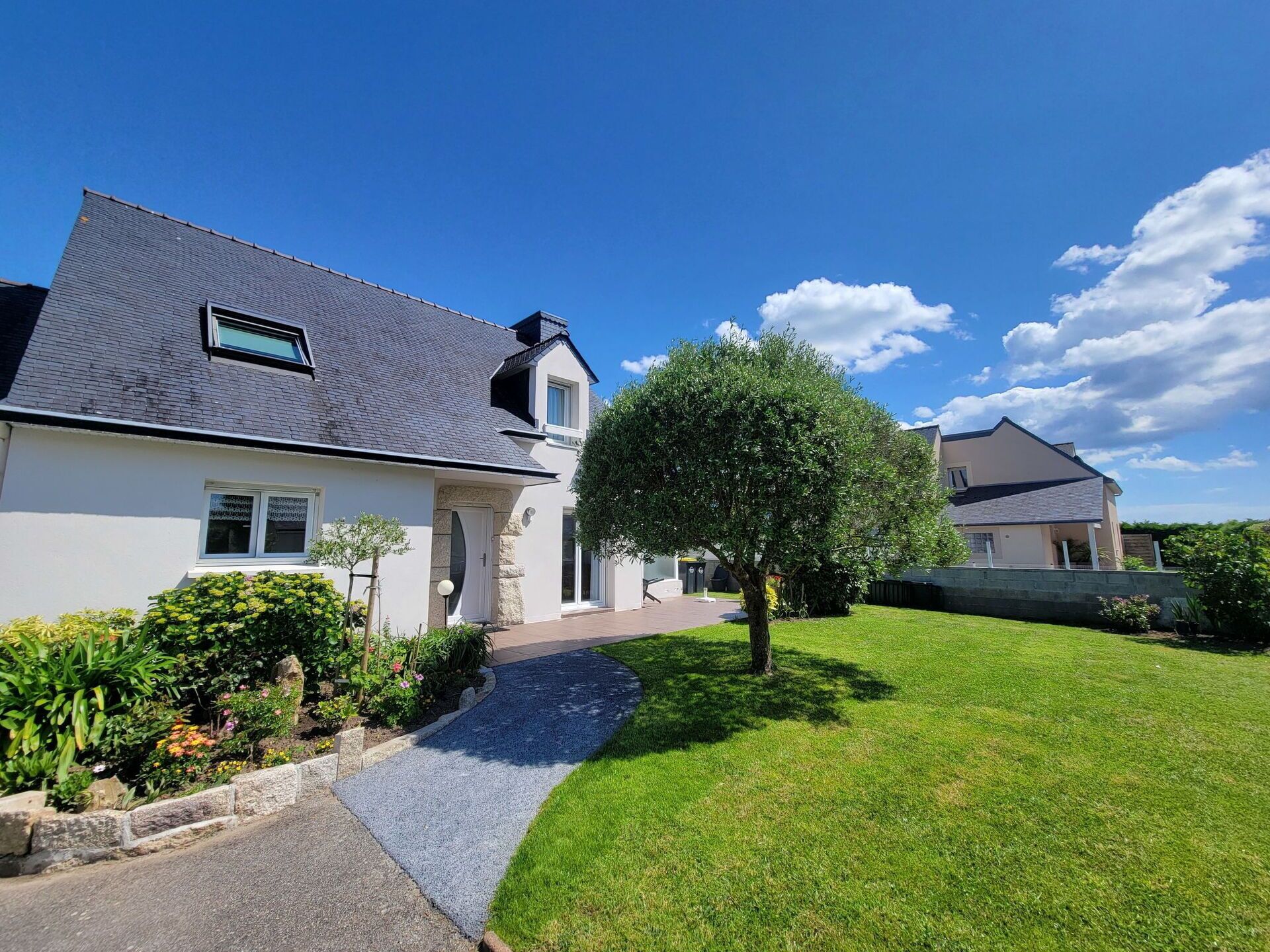 A modern two-story house with a sloped roof, a paved driveway, and a well-maintained lawn.