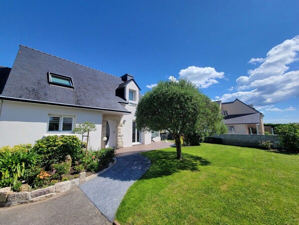 A modern two-story house with a sloped roof, a paved driveway, and a well-maintained lawn.