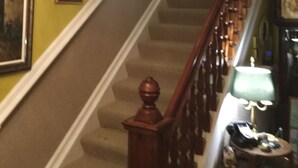 Una escalera con barandilla de madera y un candelabro colgando.