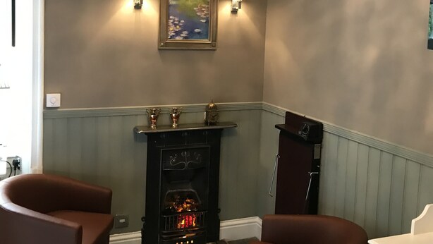 Una habitación con chimenea, dos lámparas de pared y un candelabro.