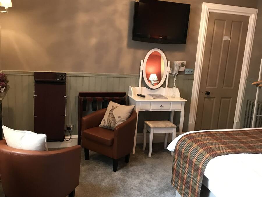 A hotel room with a bed, a desk with a mirror, a chair, a television, and a door.