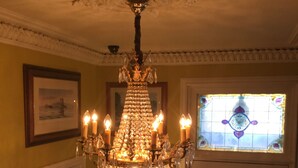 Un candelabro con múltiples velas, un cuadro enmarcado en la pared y una puerta con un vitral.