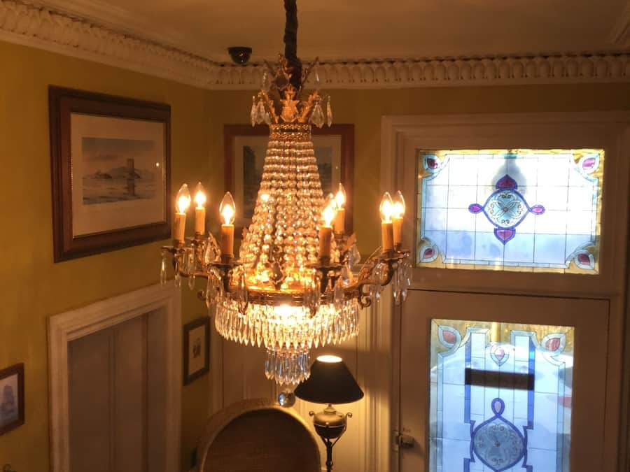 Un candelabro con múltiples velas, un cuadro enmarcado en la pared y una puerta con un vitral.